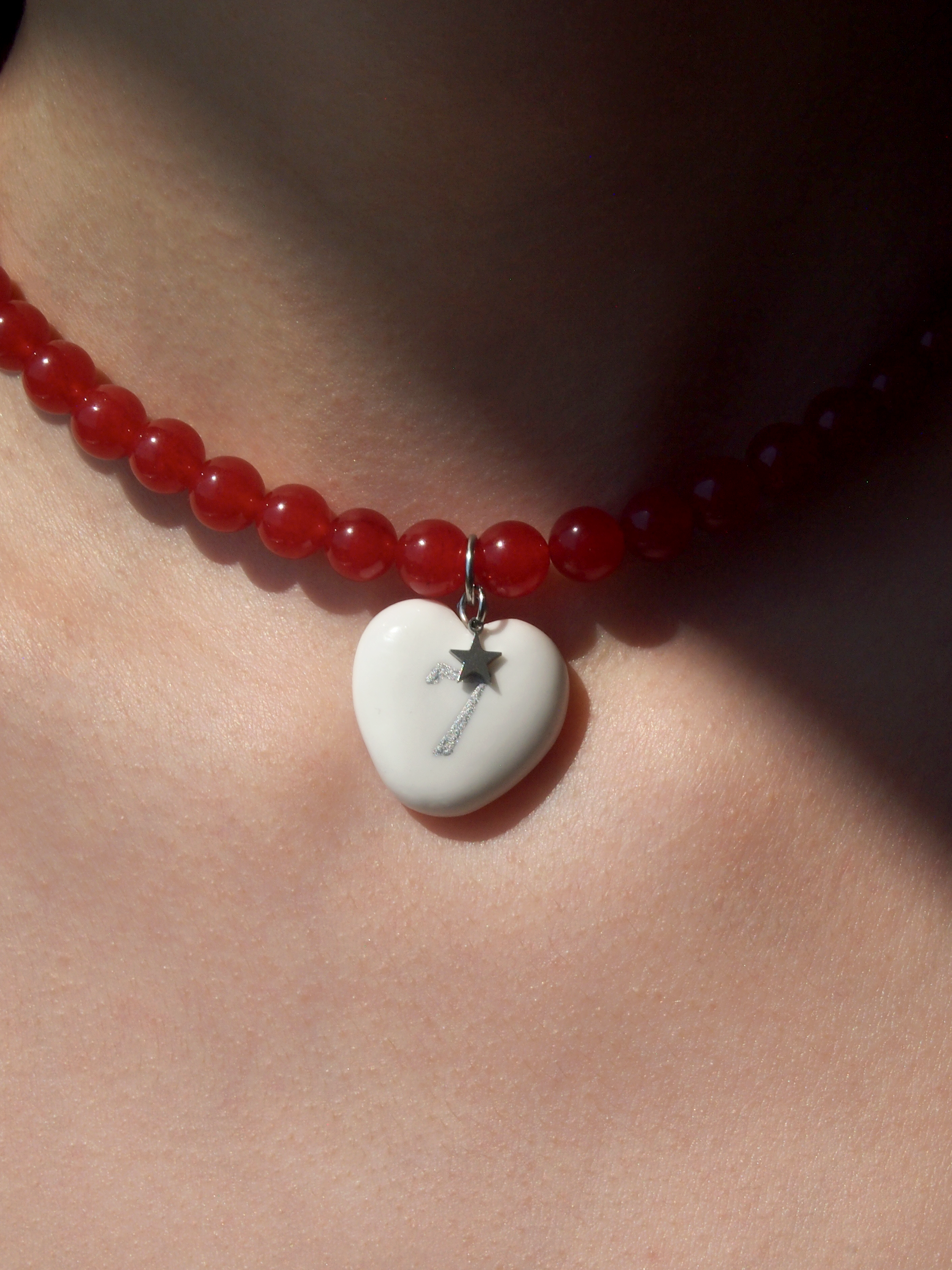 Red beaded necklace with a heart-shaped pendant featuring a key design, worn by a person.